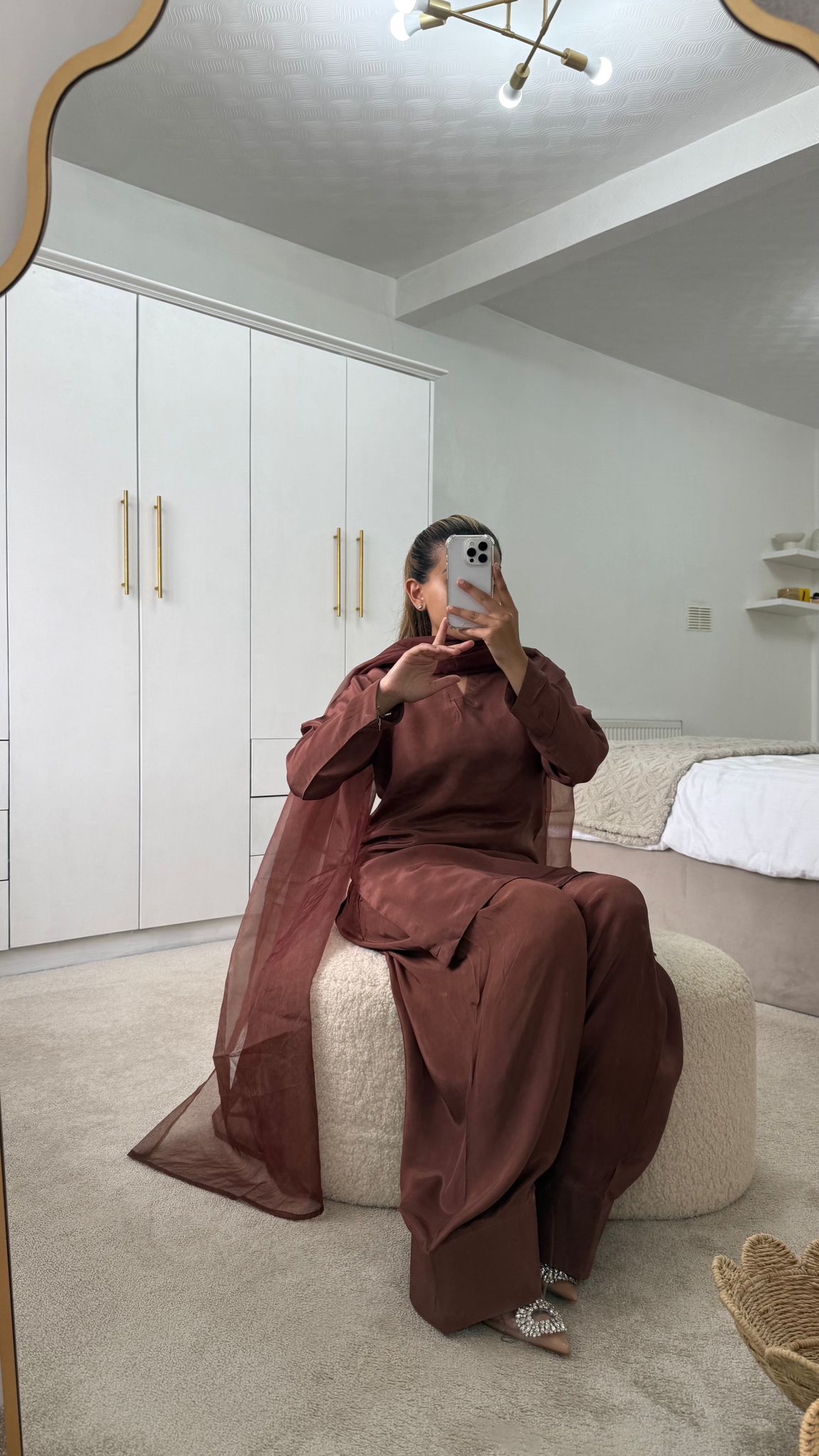 Woman in chocolate brown Farshi shalwar outfit posing in front of a mirror, showcasing contemporary elegance.