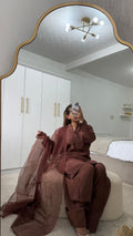 Woman in chocolate brown Farshi shalwar outfit posing in front of a mirror with flowing sheer dupatta.