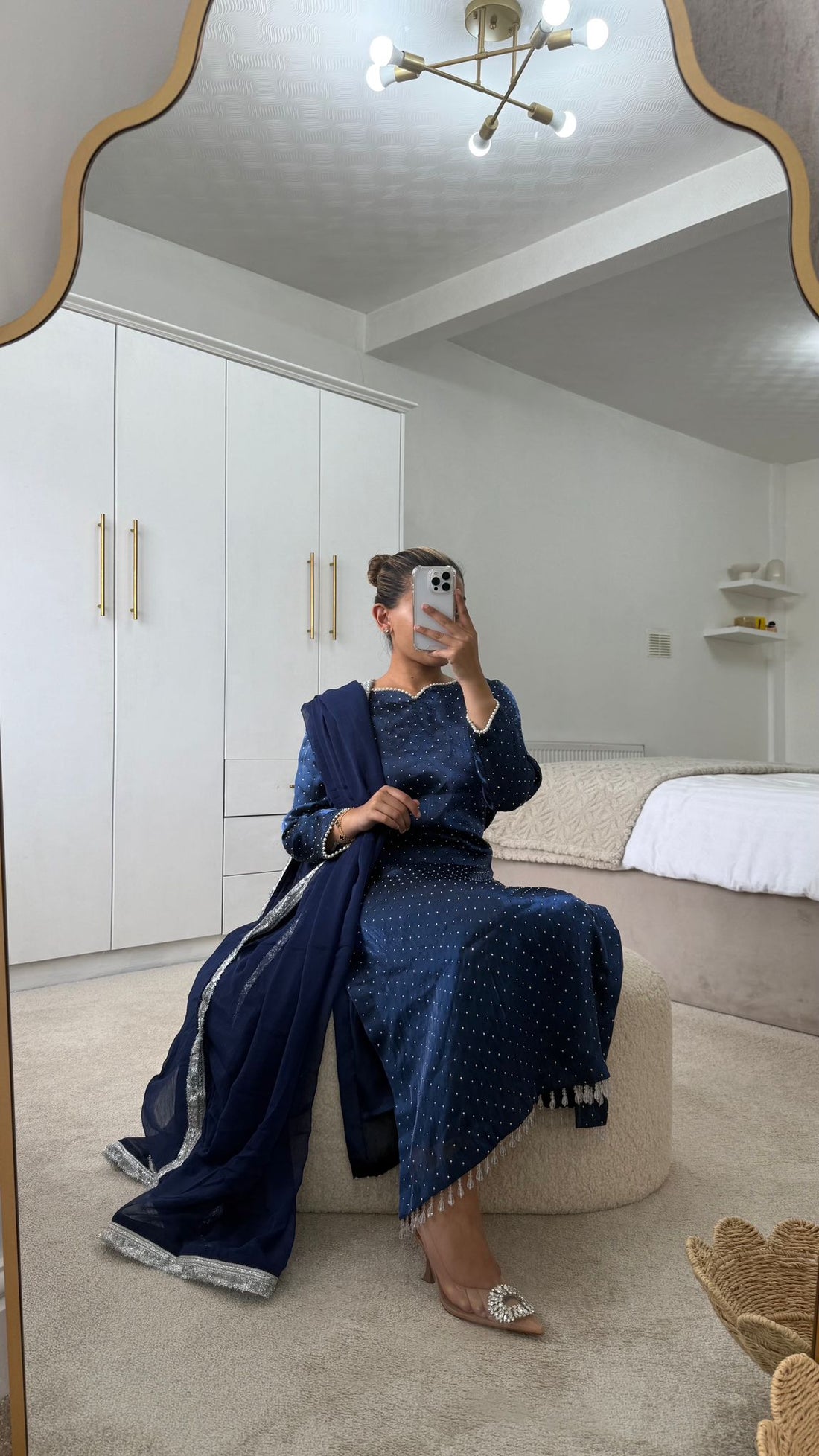 Woman in a navy long qameez and dupatta, sitting elegantly with capri trousers in a modern interior.