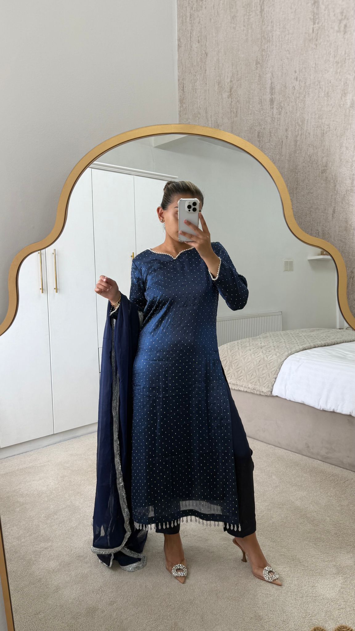 Woman in a navy long qameez with matching dupatta and capri trousers, standing in front of a mirror.